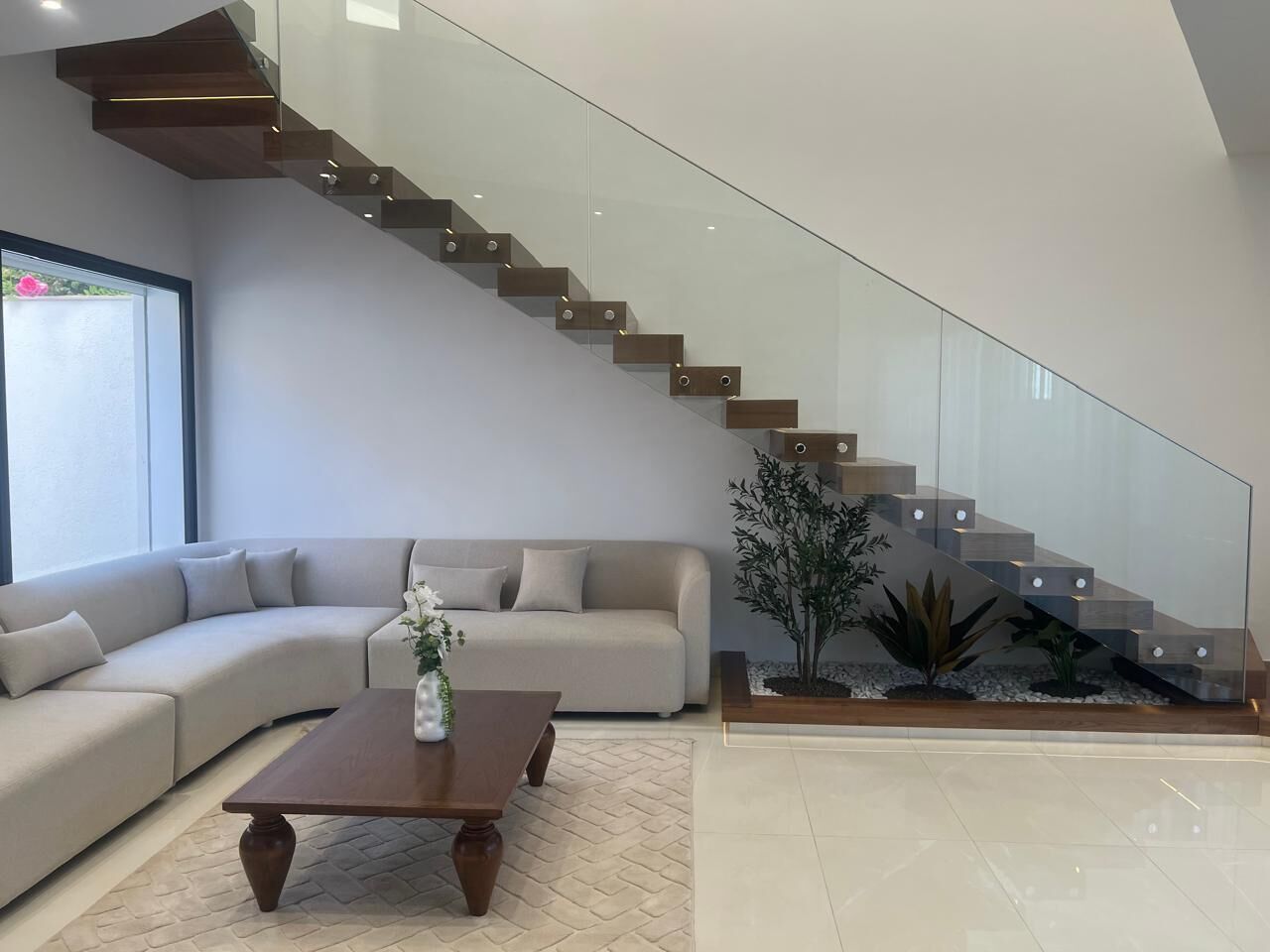 Un salon moderne avec un escalier à volutes, un canapé, une table basse et une plante.