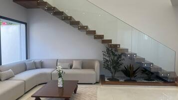 Un salon moderne avec un escalier à volutes, un canapé, une table basse et une plante.