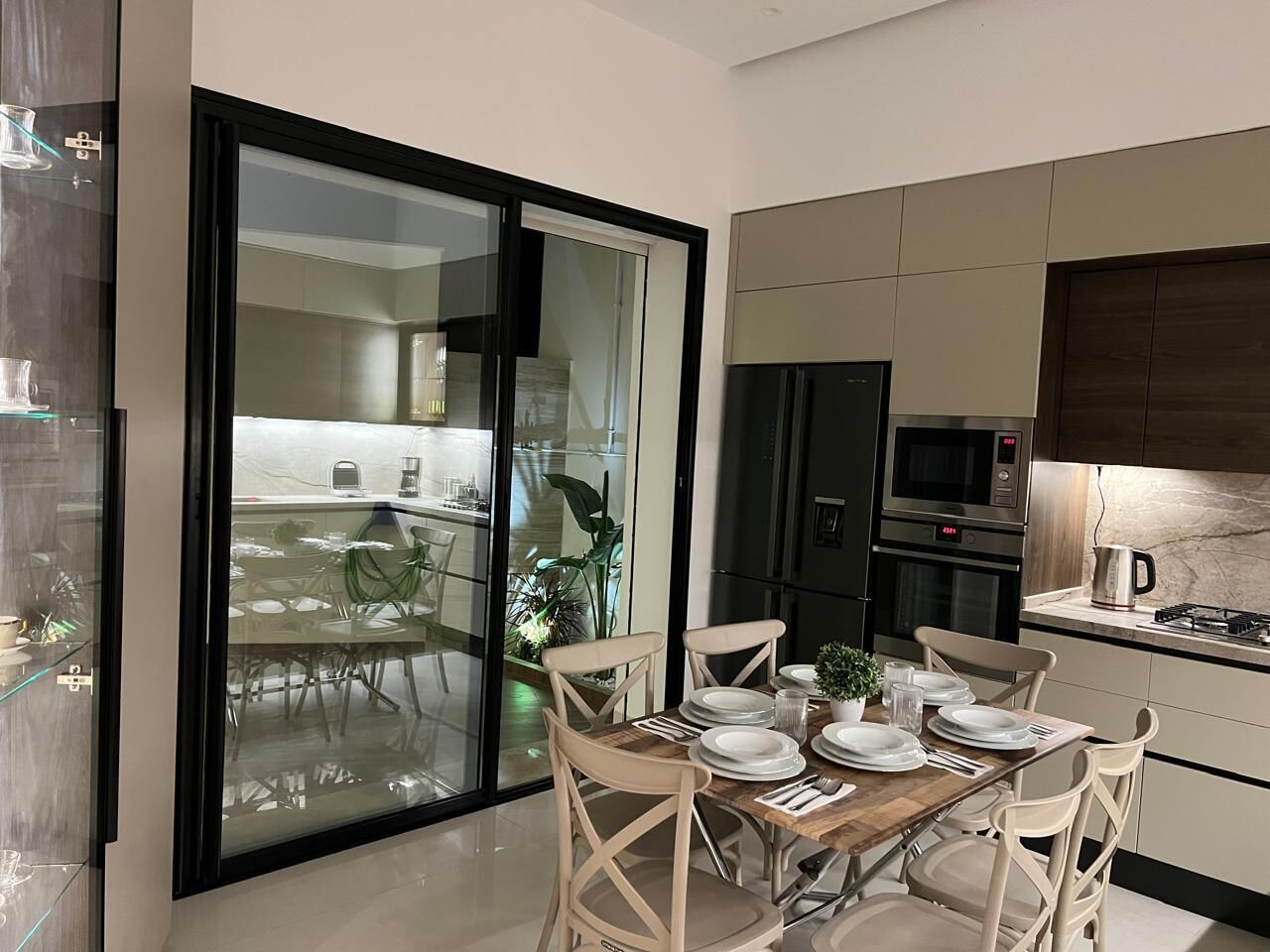 Una cocina moderna con comedor, que incluye una puerta corrediza de vidrio a un balcón, electrodomésticos integrados y un diseño limpio y contemporáneo.