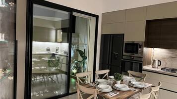 Una cocina moderna con comedor, que incluye una puerta corrediza de vidrio a un balcón, electrodomésticos integrados y un diseño limpio y contemporáneo.