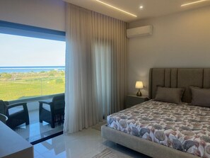 A modern bedroom with a large bed, a desk, and a view of the outdoors. - VILLA ASIA (MAAMOURA)