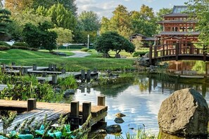 Ein traditioneller japanischer Garten mit einer hölzernen Brücke, einem Teich und einem pagodengleichen Gebäude.