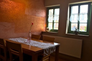 Ein Essbereich mit Tisch für vier Personen, einer Wand mit Muster, einem Fenster mit Blick und einer Heizung.