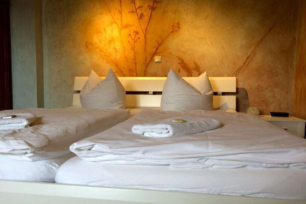 A hotel room with two beds, each with neatly folded white linens and towels.