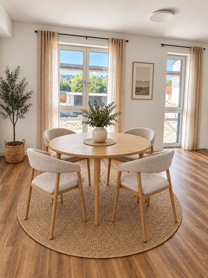 A round dining table with four chairs, a potted plant, and a framed picture on the wall.