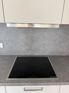 A kitchen with a Bosch induction cooktop and a stainless steel range hood.