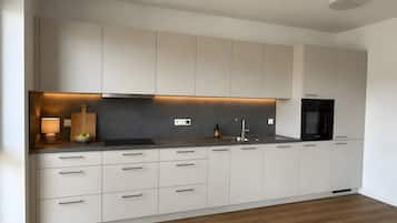 Eine moderne Küche mit weißen Schränken, einer schwarzen Arbeitsplatte und einem eingebauten Backofen.