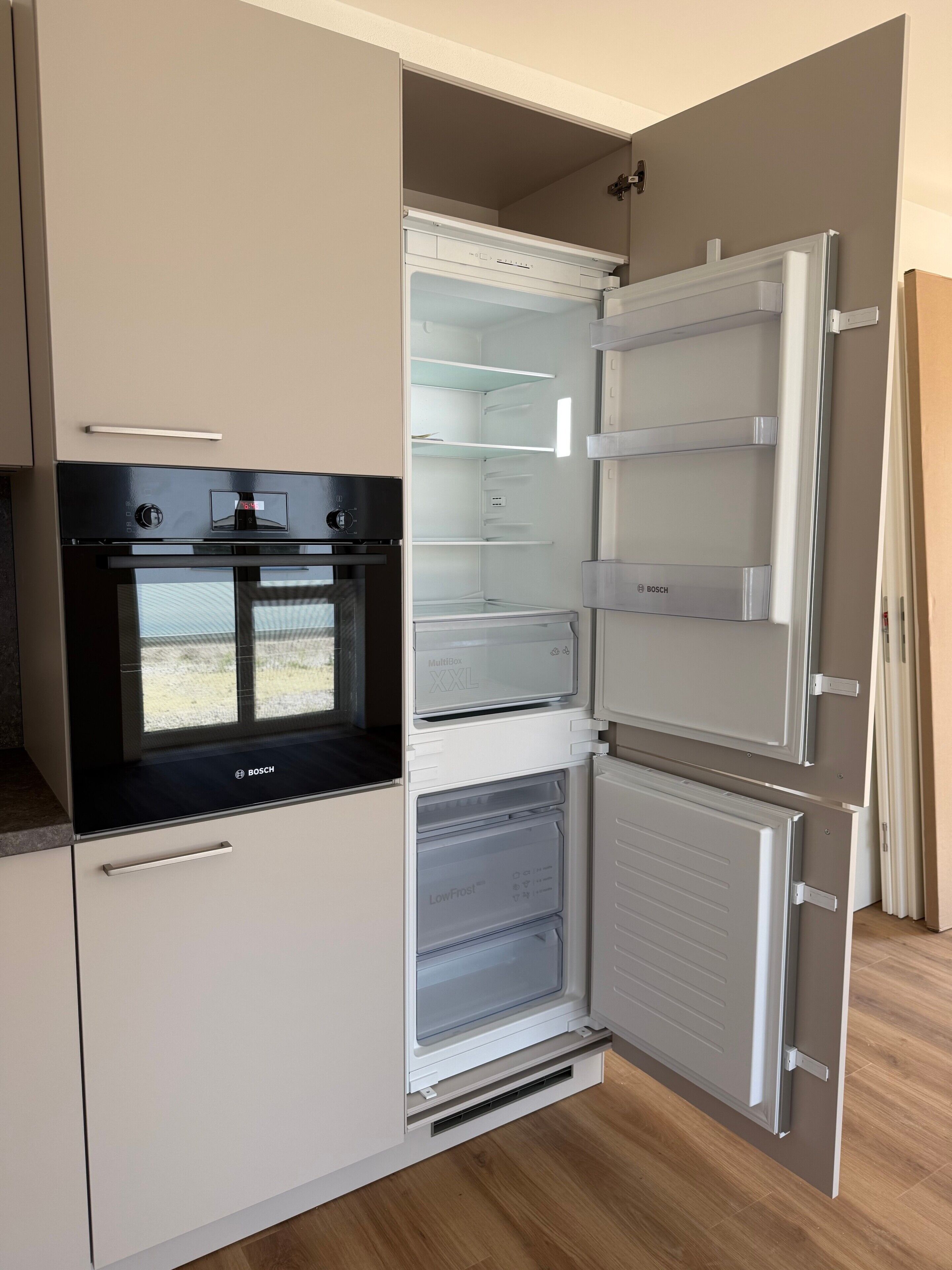 Een keuken met een inbouwoven, een koelkast met meerdere vakken en een magnetron.