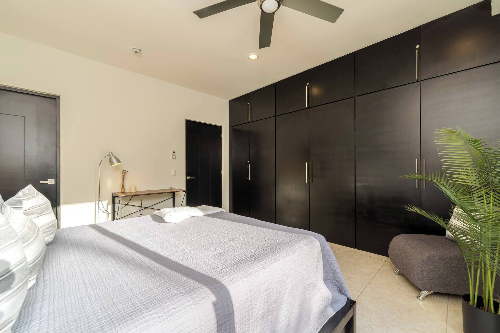 Un dormitorio moderno con cama, escritorio y armario.