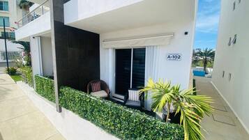 A modern apartment with a balcony, a sliding glass door, and a small seating area.