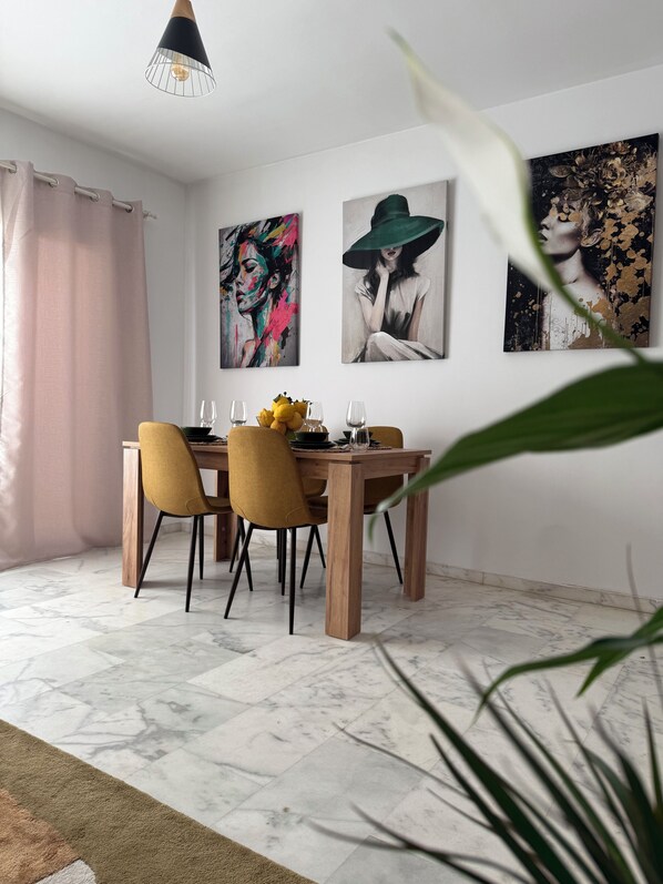 A dining area with a wooden table, two chairs, and a vase of flowers. - Vrbo Property (Cancelada)
