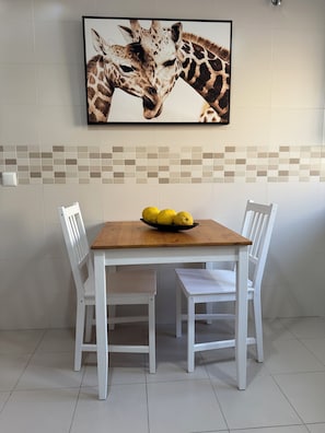 A dining area with a wooden table, white chairs, and a framed giraffe picture on the wall. - Your Sunny Getaway in Spain - Casa de Palmeras (Cancelada)