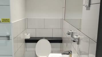 Un baño pequeño y moderno con inodoro, lavamanos y espejo.