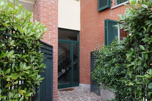 A brick building with a green door and window shutters, surrounded by greenery. - A bright 85 square meters apartment, perfect for four people, located on the second floor of a modern building with an elevator (NOT accessible to people with disabilities).The property is situated opposite the Monza circuit, near the first chicane and t (Biassono)
