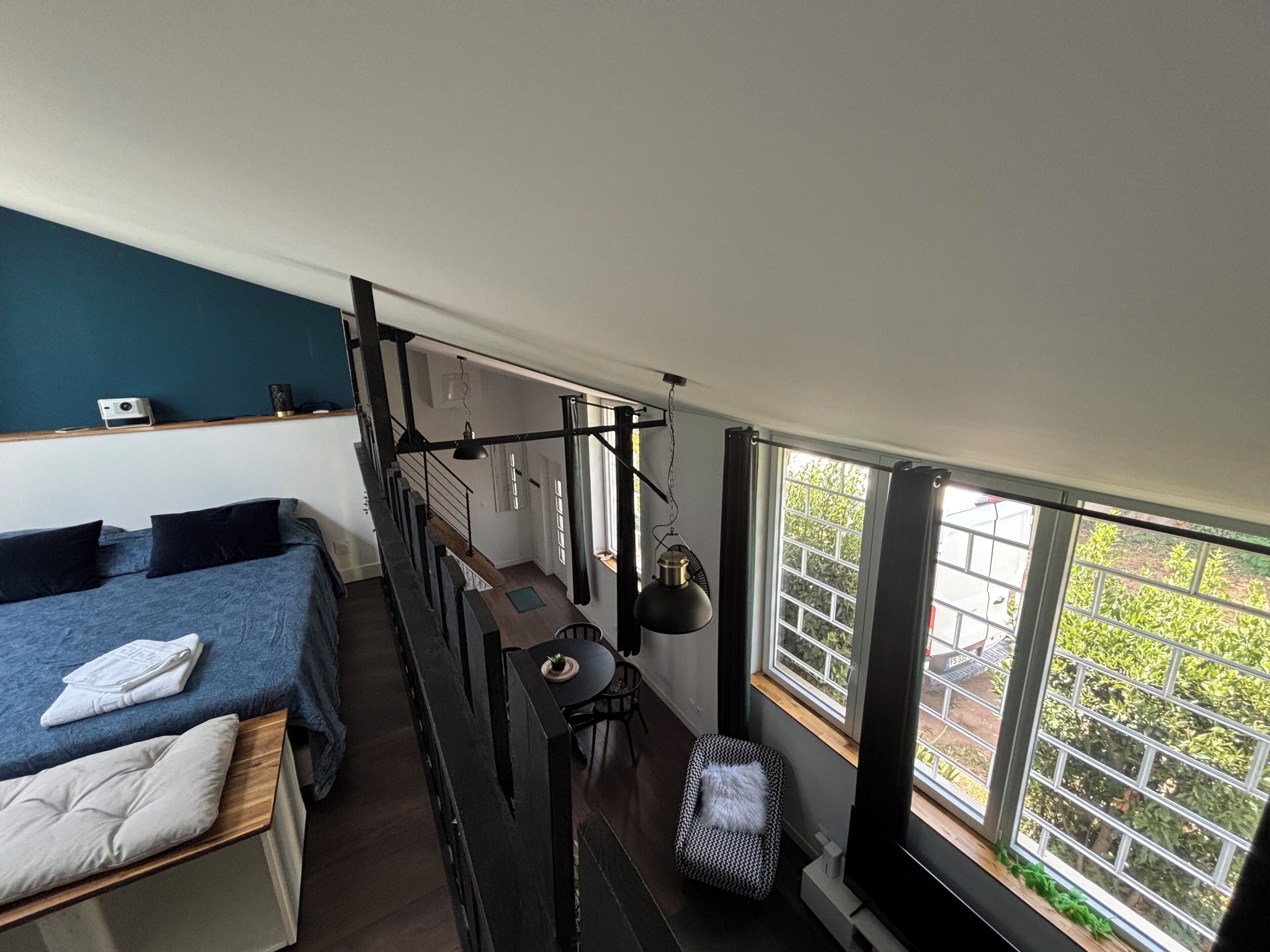 A compact room with a bed, a small table, and a window with a view of greenery.