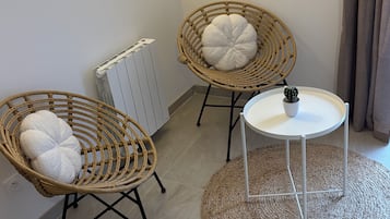 Ett rum med två fåtöljer i rotting, ett litet vitt bord och ett element.