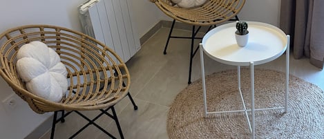 A room with two wicker chairs, a small white table, and a radiator.