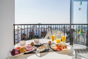 Una mesa de desayuno con vista a edificios y una barandilla de balcón.