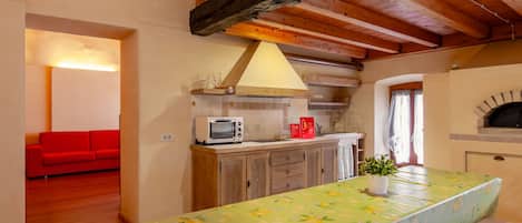 Cocina compacta con microondas, horno pequeño y mesa con mantel floral.