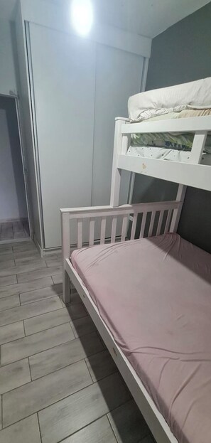 A bunk bed with a lower bunk and a single bed, a wardrobe, and a tiled floor. - Great house in Itanhaém (Itanhaém)