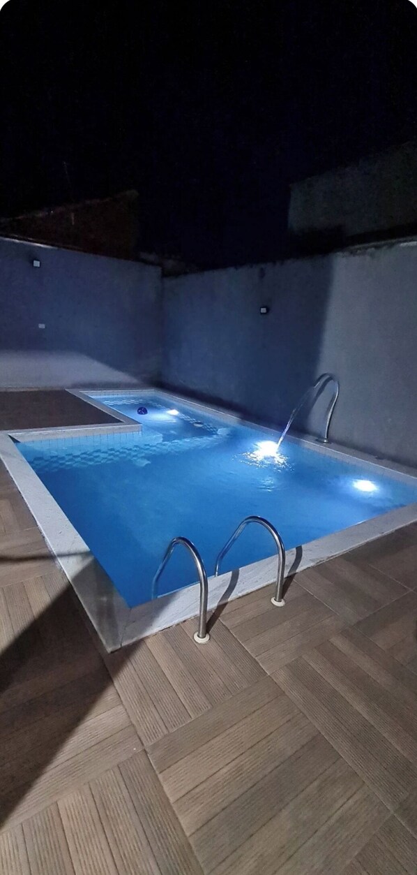 An outdoor swimming pool with a tiled edge and metal handrails. - Great house in Itanhaém (Itanhaém)