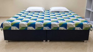 Un lit double avec une couvre-lit à motifs, deux oreillers et une tête de lit de couleur foncée.