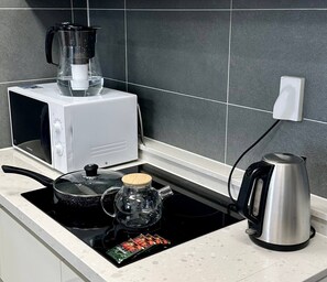 A kitchen with a microwave, kettle, and a coffee maker on the countertop.