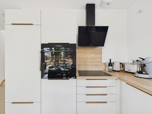 A modern kitchen with a Bosch refrigerator, a black range hood, and a wooden countertop with a coffee machine. - Fully equipped house for 6 with garden (Saint-Hilaire-de-Riez)