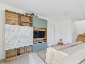 A living room with a sofa, a TV, and a wooden entertainment unit. - Fully equipped house for 6 with garden (Saint-Hilaire-de-Riez)