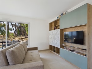 A modern living room with a sofa, a television, and a wooden entertainment unit. - Fully equipped house for 6 with garden (Saint-Hilaire-de-Riez)