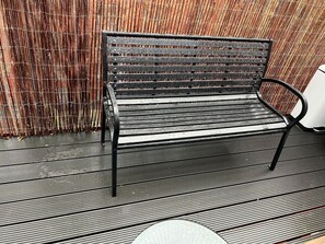 Een metalen bank met een rugleuning en armleuningen, op een geruit vloertje.