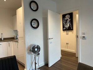 Een moderne keuken met witte kasten, een aanrecht en een wandventilator.