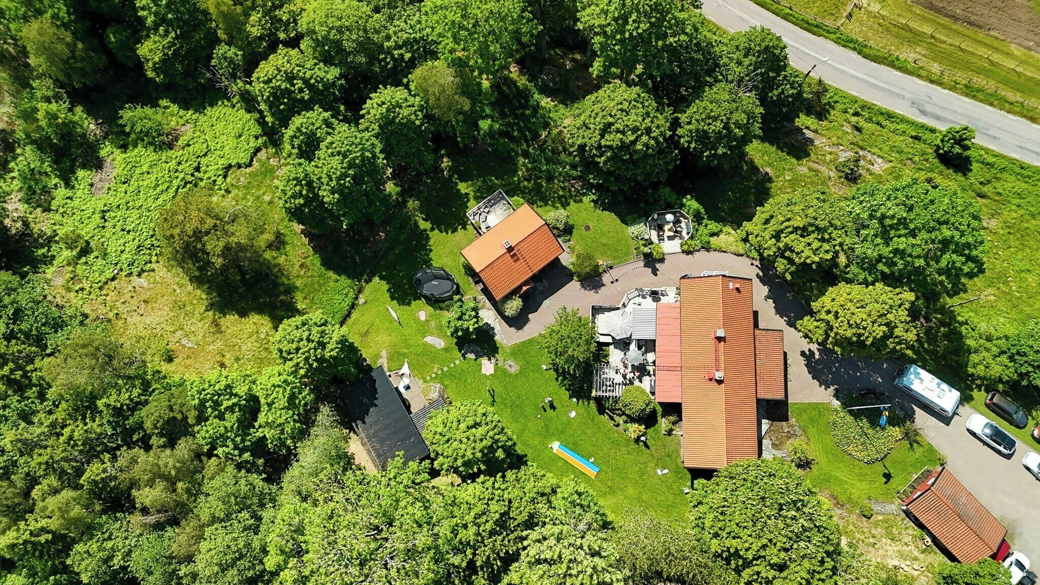 Ett flygbildsbild av ett bostadsområde med flera hus, en väg och omgivande grönska.