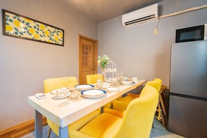 A dining area with a table set for four, yellow chairs, a white tablecloth, and a small plant centerpiece.