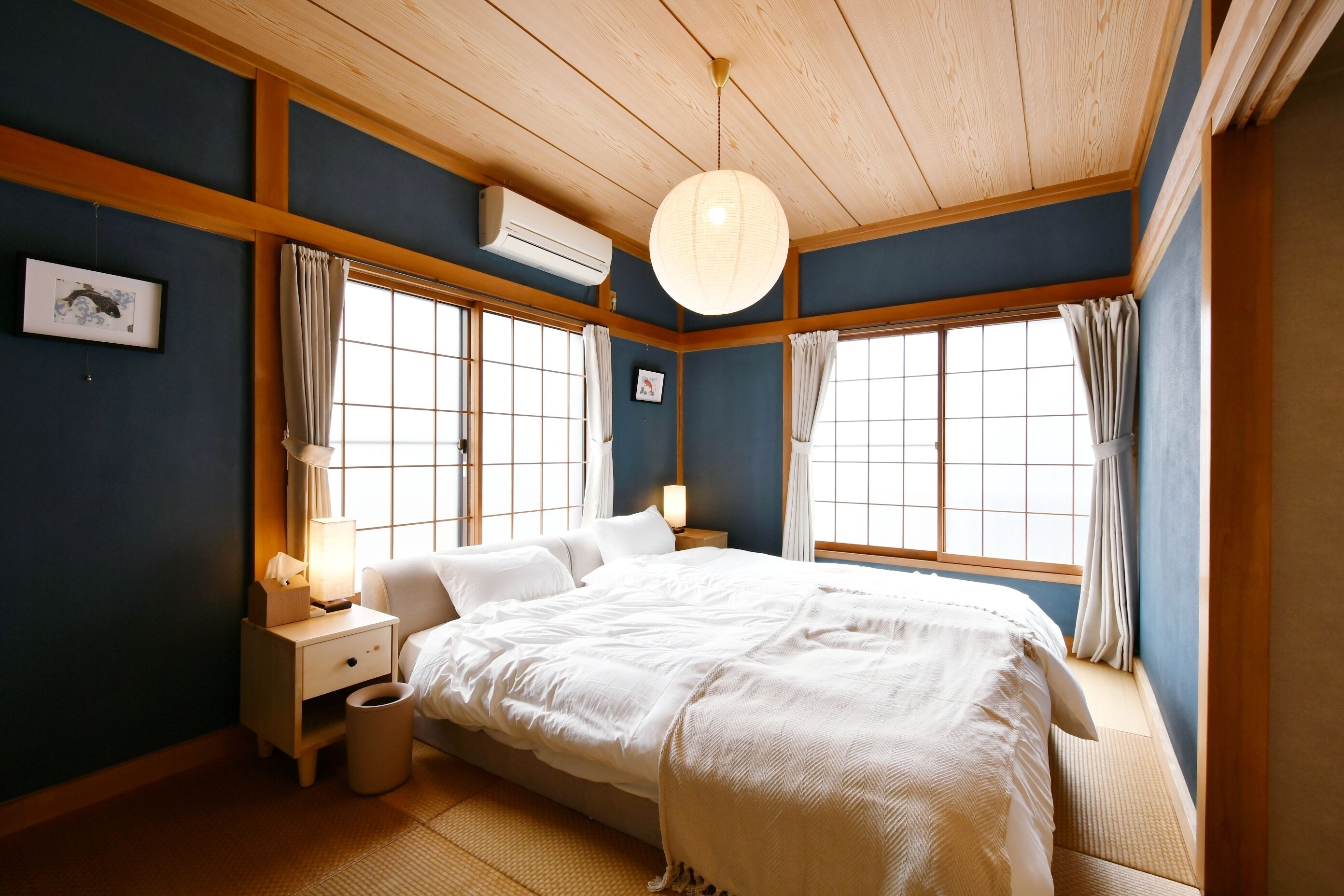A traditional Japanese-style bedroom with a large bed, wooden beams, and sliding doors.