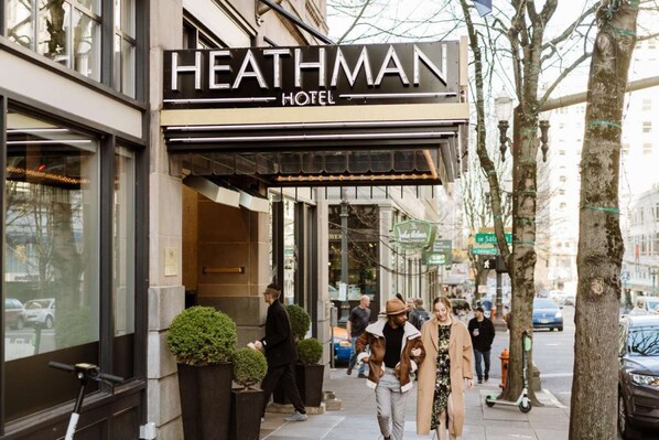 La façade de l’hôtel Heathman, avec une enseigne bien visible, une entrée abritée et un trottoir bordé de piétons.