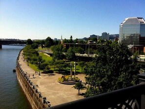 A riverside promenade with a bridge, trees, and modern buildings in the background. - Steps to Powell’s & Art Museum | Pet-friendly. Gym (Portland)
