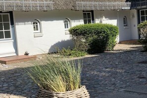 A building with white walls, multiple windows, and a cobblestone pathway. - Holiday apartment with 1 bedroom (Rantum, Sylt)