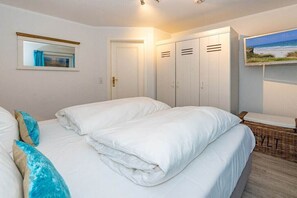 Une chambre à coucher avec un lit, une armoire et un téléviseur fixé au mur.