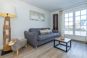 A living room with a grey sofa, a wooden coffee table, a lamp, and a sheep-shaped sculpture. - Holiday apartment with 1 bedroom (Rantum, Sylt)