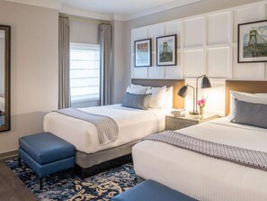 Une chambre d’hôtel avec deux lits, une table de chevet, une lampe et une fenêtre avec des rideaux.