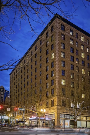 A multi-story building with a brick facade, multiple windows, and a street-level entrance with signage. - Walk to Schnitzer & Powell’s | Bike & Pet-friendly (Portland)