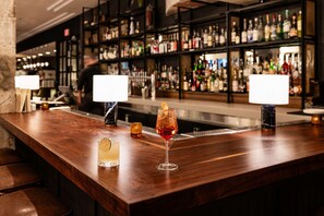 A bar area with a wooden counter, two bar lamps, and a variety of bottles in the background. - Walk to Schnitzer & Powell’s | Bike & Pet-friendly (Portland)