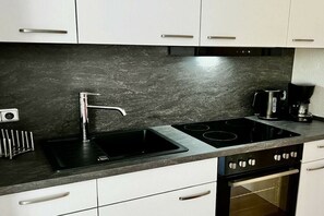 Een moderne keuken met een zwart aanrecht, roestvrijstalen apparatuur en witte keukenkastjes.