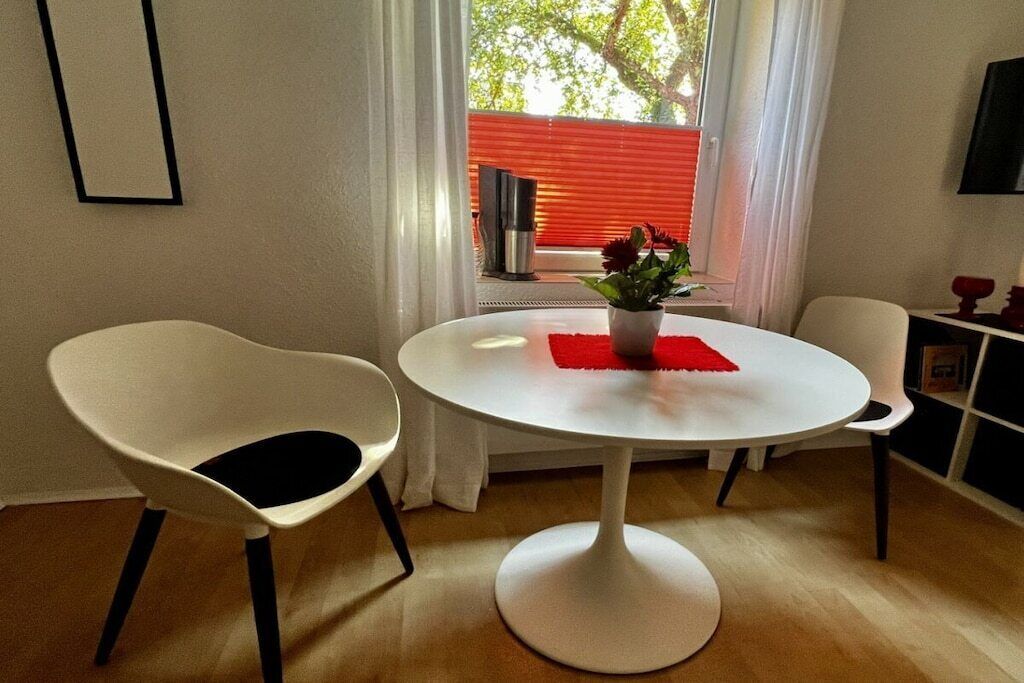 Een eethoek met een ronde tafel, twee stoelen, een potplant en een rode placemat.