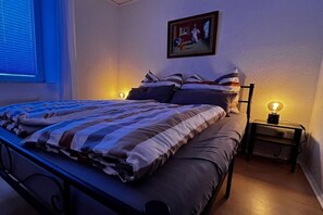 Ein Schlafzimmer mit einem Bett, einem Nachttisch, einer Lampe und einem Bild an der Wand.
