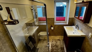 Ein Badezimmer mit Duschkabine, Toilette, Waschbecken und Fenster.