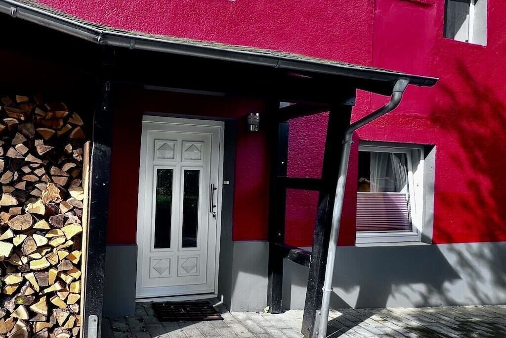 Een gebouw met een rode gevel, een witte deur en een raam met een rode omlijsting.