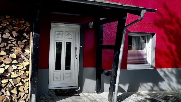 Ein Gebäude mit roter Fassade, einer weißen Tür und einem Fenster mit rotem Rahmen.