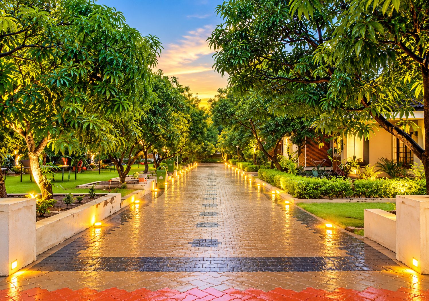 A paved pathway lined with trees and illuminated by ground lights, leading to a building with a modern design.